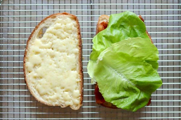 Two slices of bread with melted cheese on one and lettuce on the other