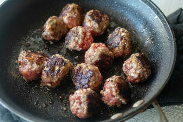Brown sausage meatballs before putting them in the slow cooker