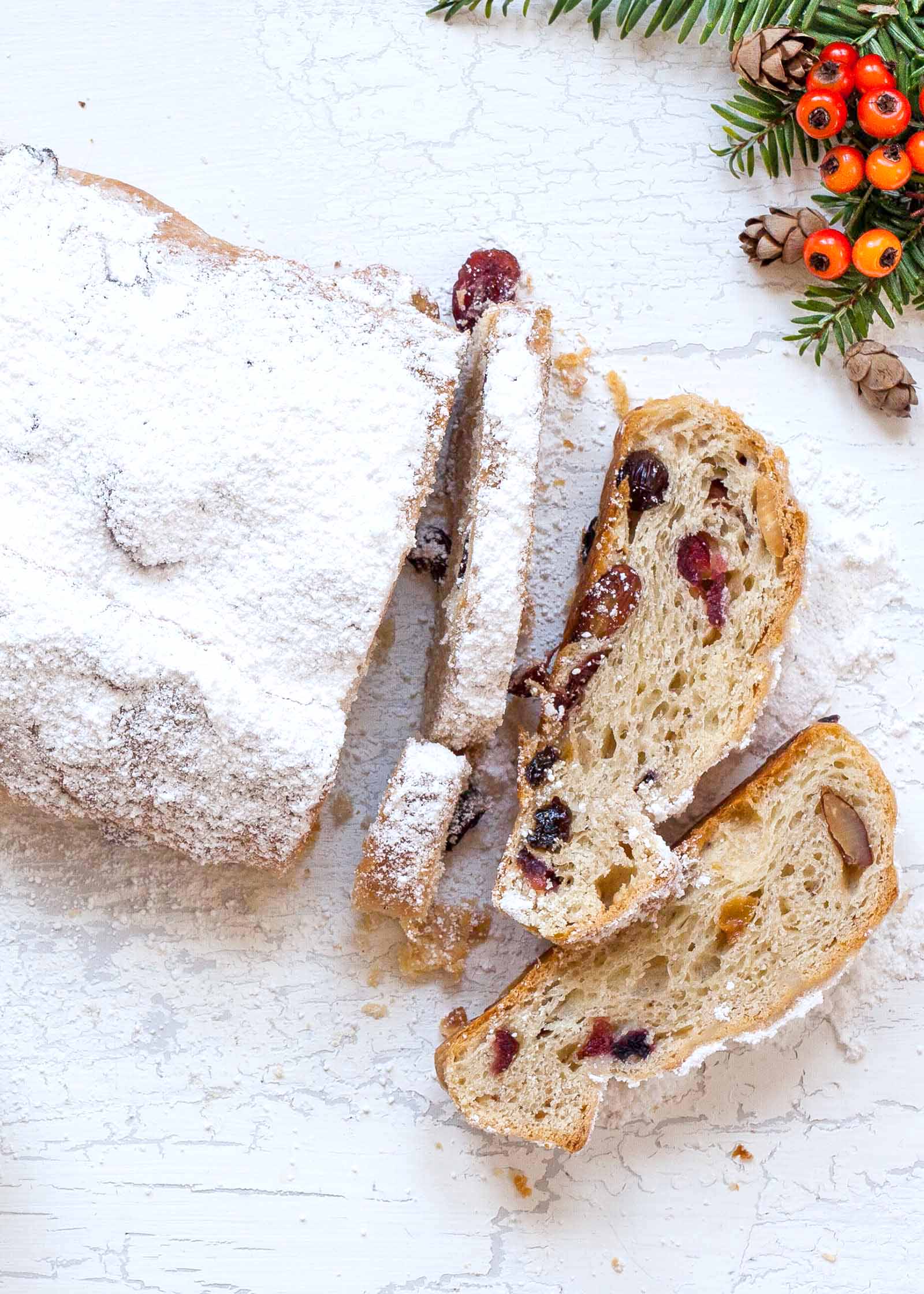 Stollen Christmas Bread filled with rum-soaked dried fruit coated with powdered sugar and sliced on a platter..