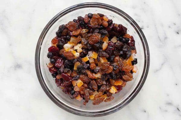 Mixed dried, rum-soaked fruit for German Stollen Christmas bread in a glass bowl.