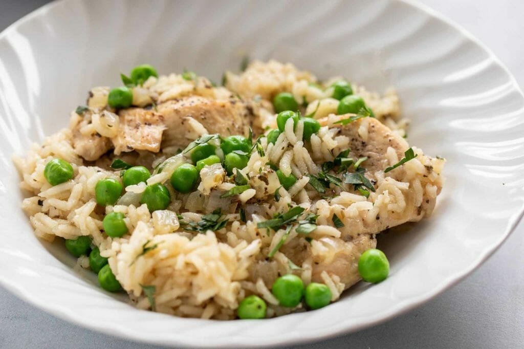 A plate of chicken and rice with peas