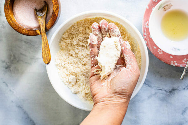 Woman's hand mixing Ingredients to make dough and grabing a fistful of it in her hands.