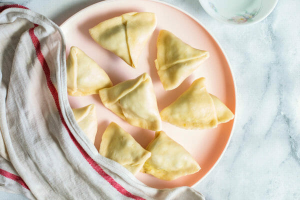 Pink plate with raw vegetables samosas.