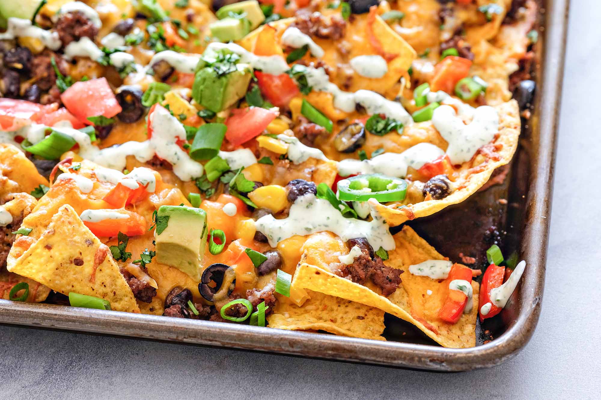 Corner of a sheet pan loaded with homemade nachos
