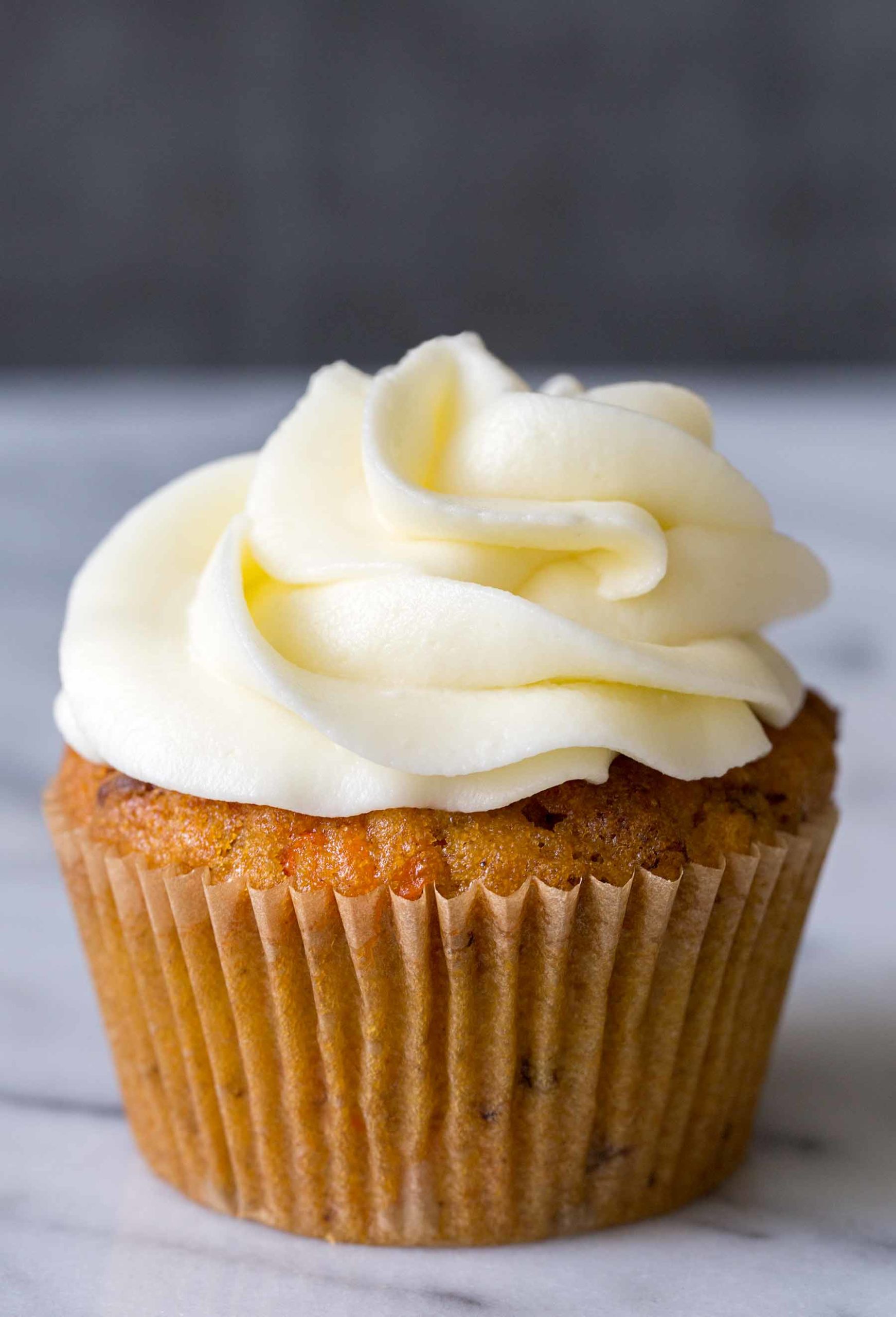 One single carrot cake cupcake topped with cream cheese frosting