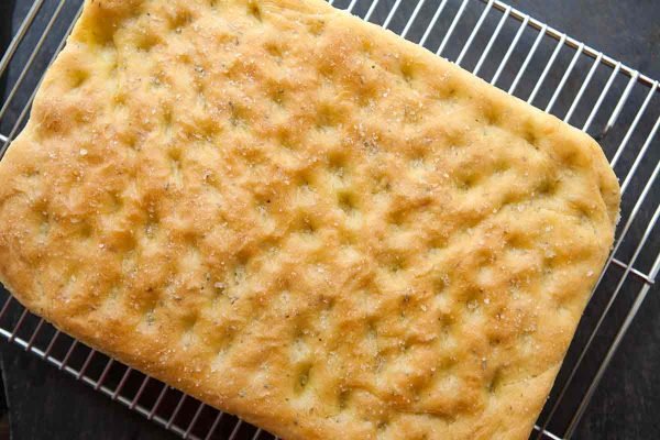 Easy rosemary focaccia dimpled on top and cooling on a rack