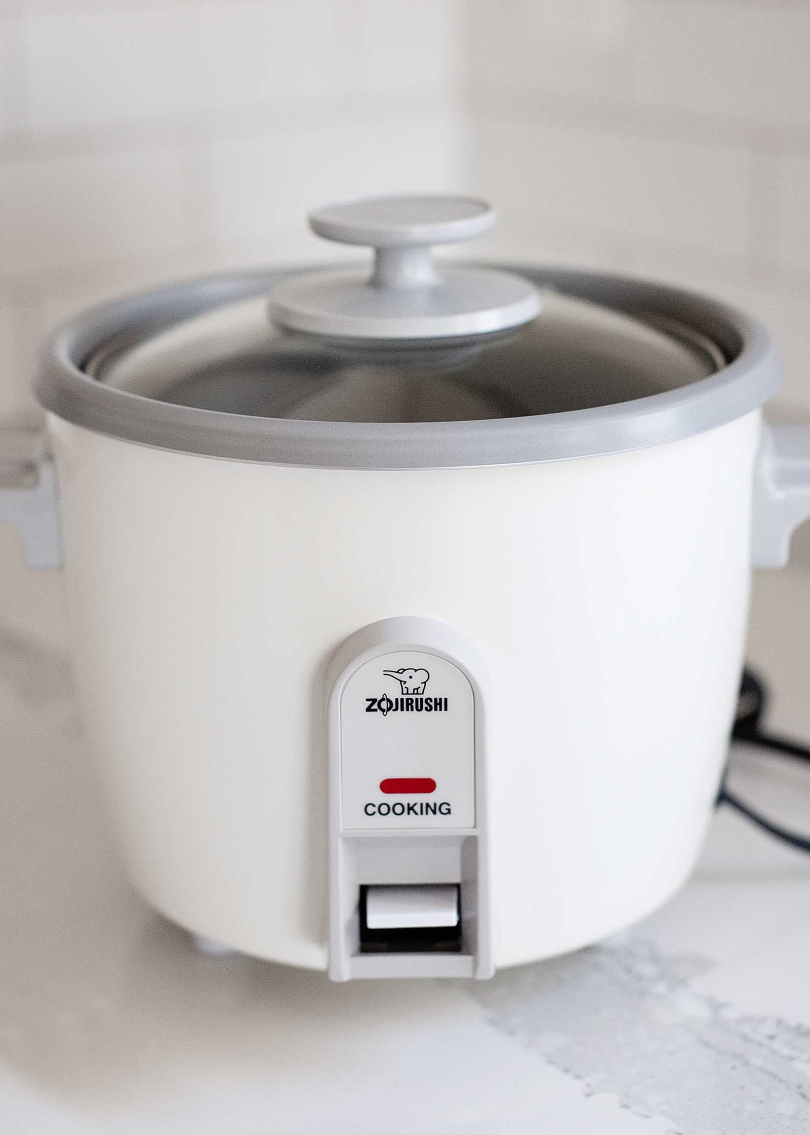 Side view of a Zojirushi rice cooker on a white countertop.