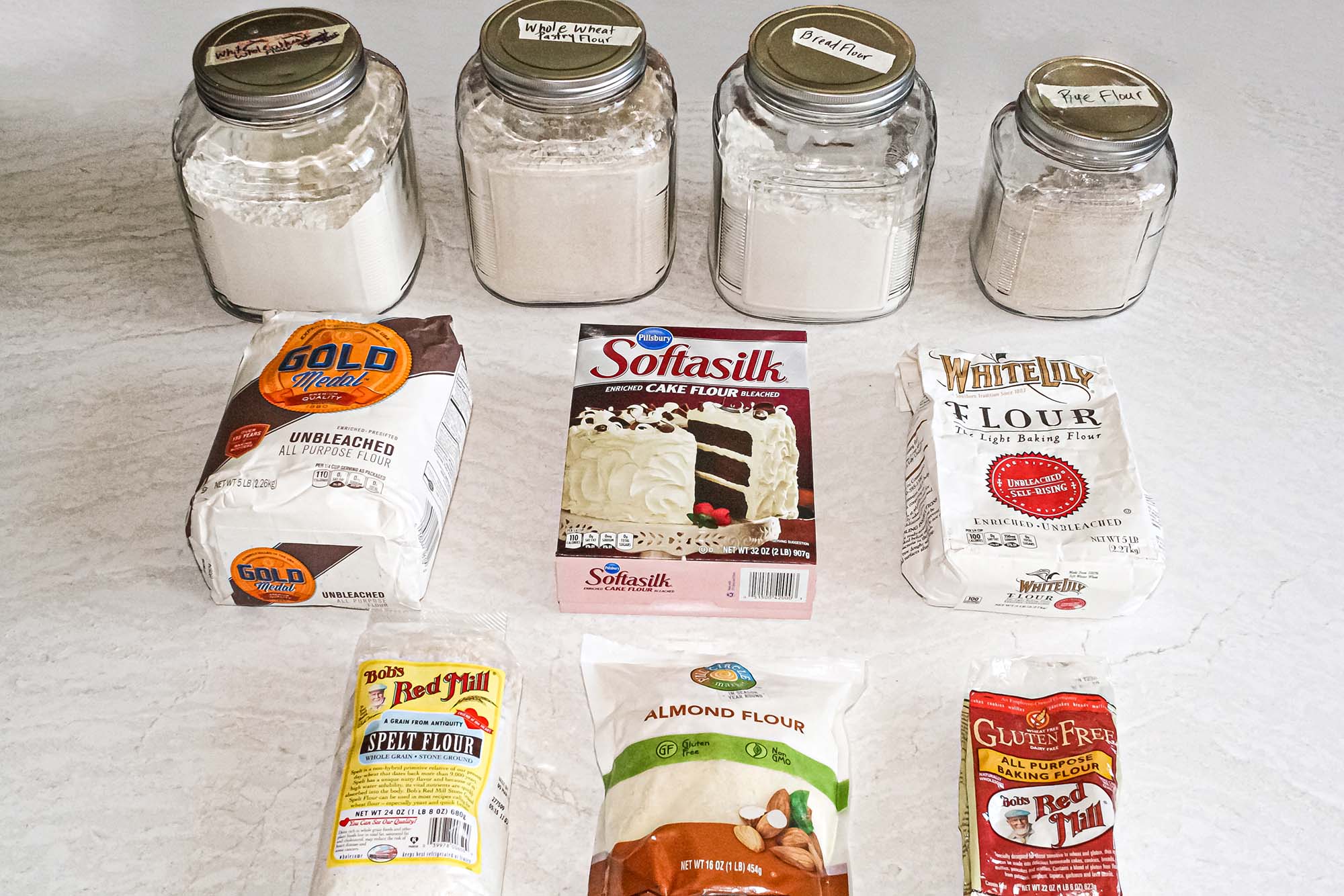Side view of different types of flour in canisters and packages to show whole wheat flour substitutions.