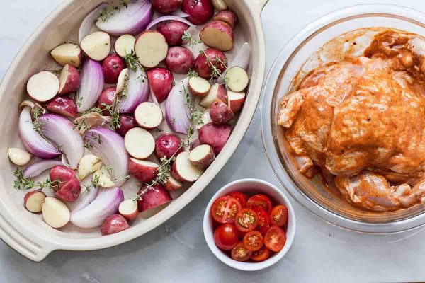 Layer the potatoes and onions for paprika chicken in a baking dish