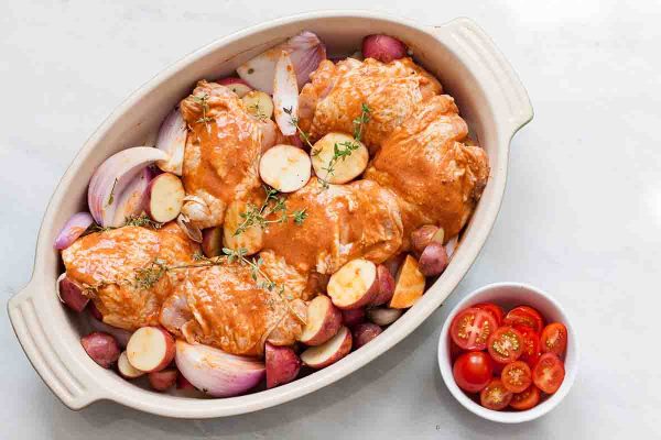 Place the chicken and potatoes on top of the onions in a baking dish