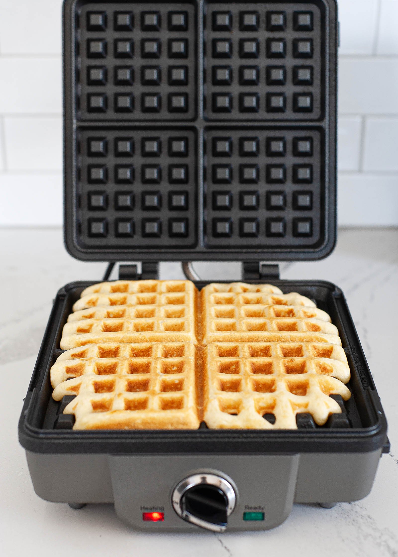 An open waffle maker with a cooked waffle inside.