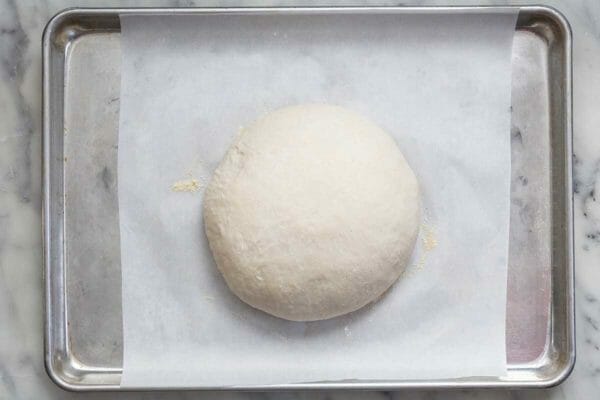 No-Knead Dutch Oven Bread dough on a baking sheet covered in parchment paper. The dough is proofed and smooth.