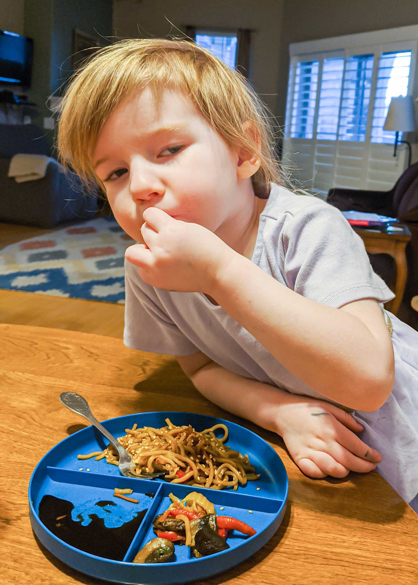 Young boy eating easy vegetable lo mein at the kitchen table.