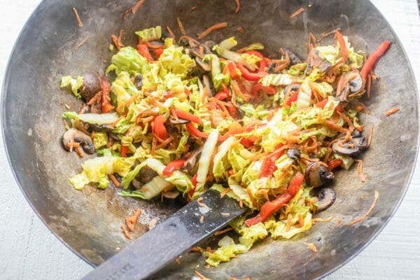Shredded cabbage, carrots, mushrooms and red peppers in a wok for homemade vegetable Lo Mein.