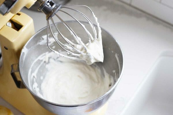 Overhead view of whipped yogurt cream in a stand mixer bowl for a light strawberry shortcake.