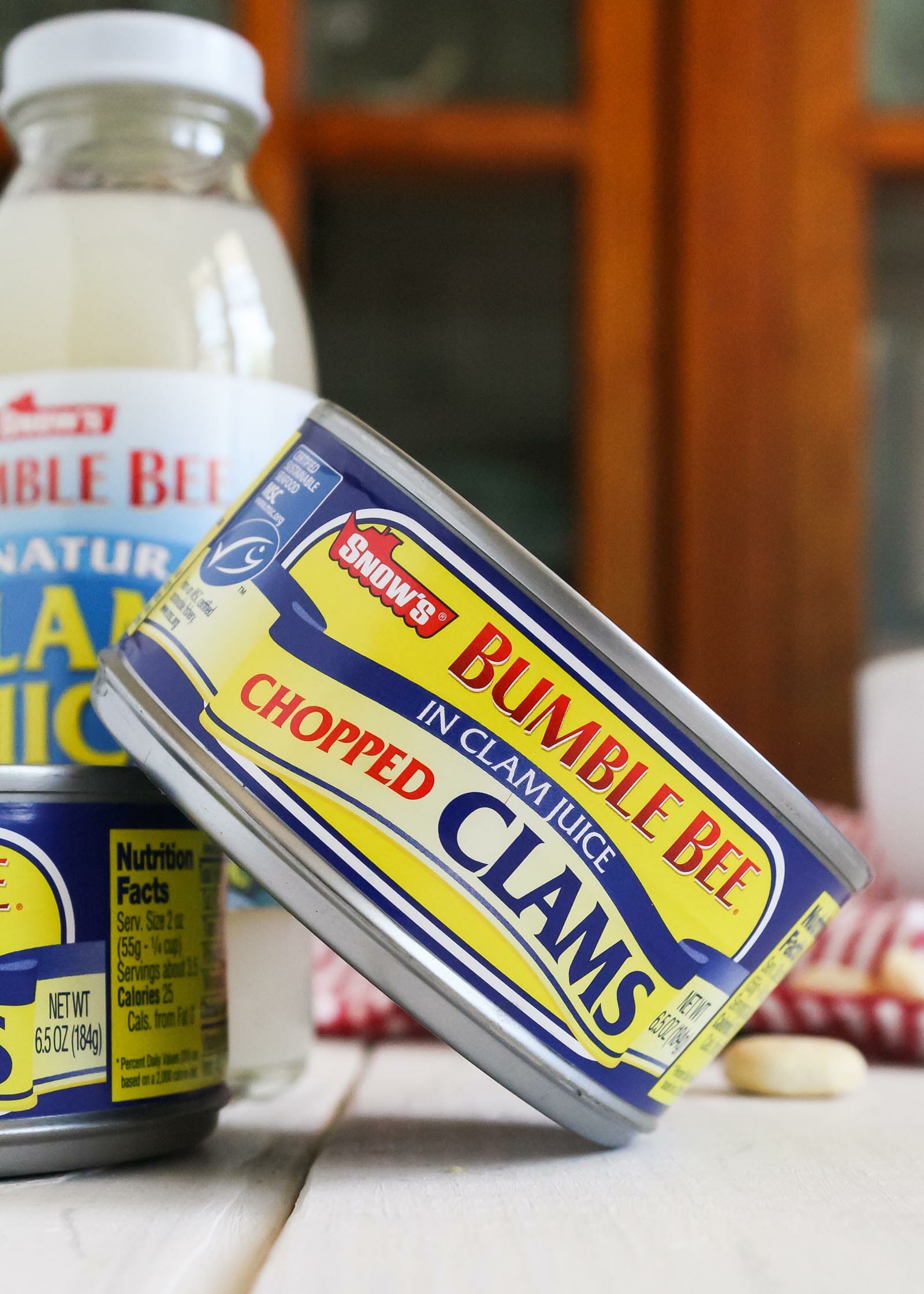 A guide to canned clams with a close up of canned clams and a bottle of clam juice in the background.