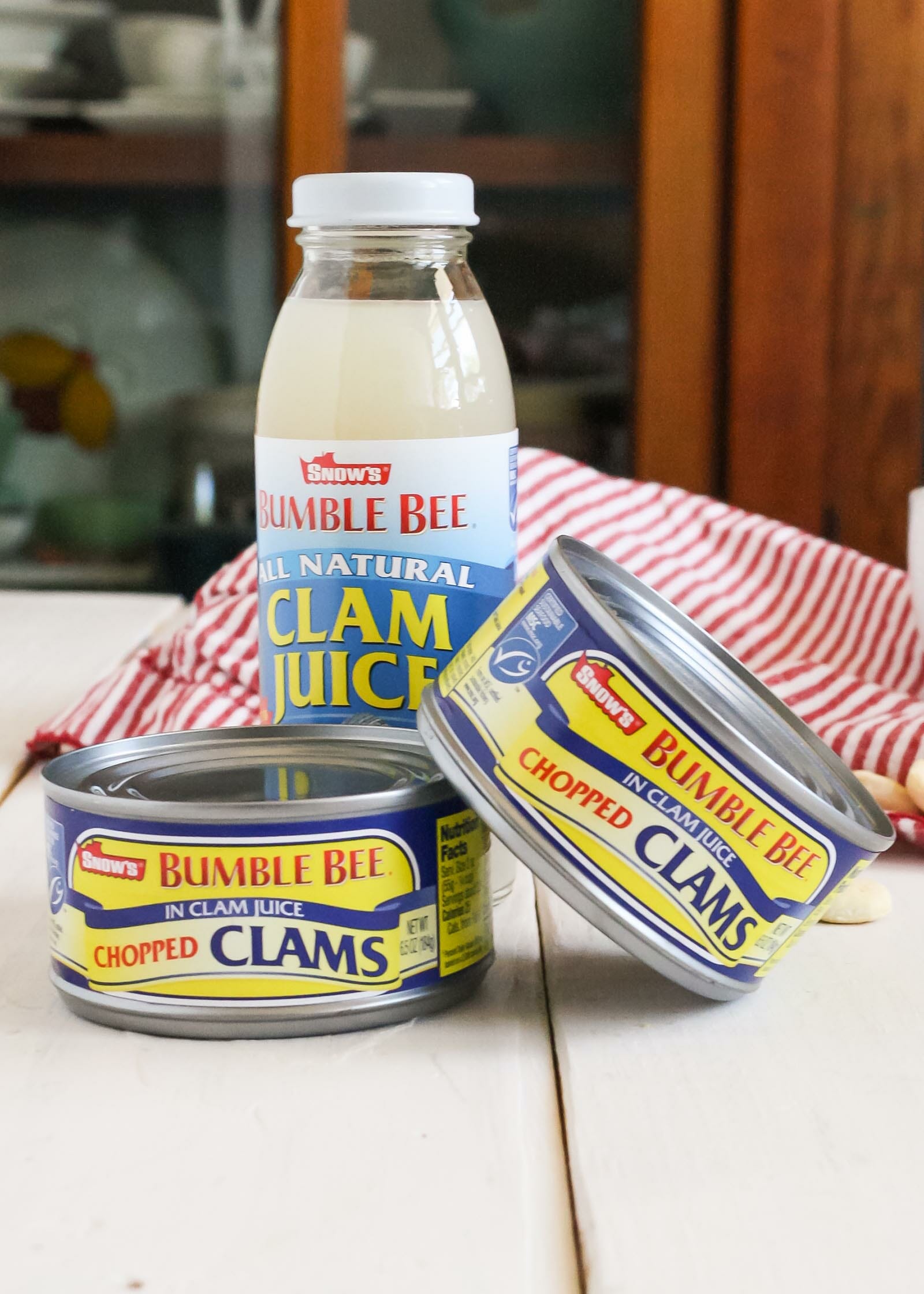 Two cans of clams and a bottle of clam juice set on a table. Why you should buy canned clams