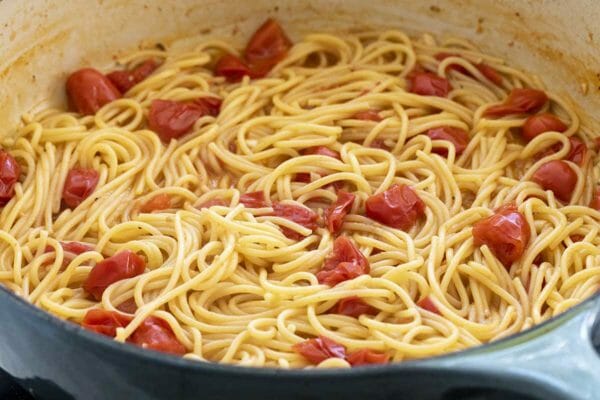 Dutch oven with easy chicken pasta skillet dinner being made. Spaghetti noodles with pasta are cooked inside the pot.