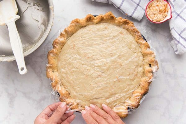 Saran wrap is placed on the top of the pie and filling for an easy coconut cream pie.