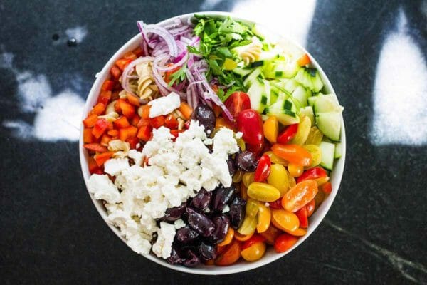 Best pasta salad with chopped vegetables, feta cheese and olives in a bowl.