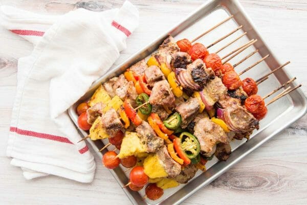 Pork kebabs with grilled pineapple on a quarter sheet pan.