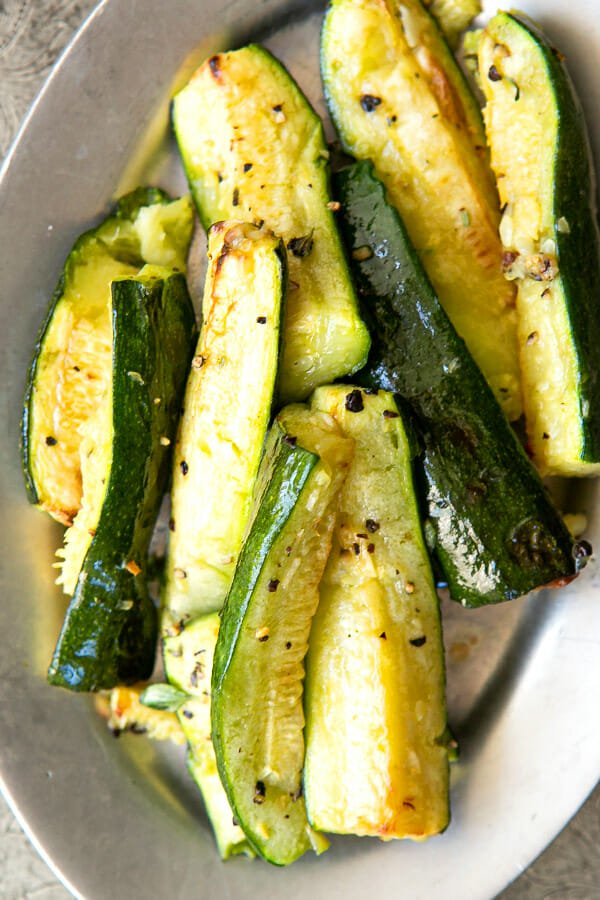 Roasted Zucchini with Garlic on a serving platter sprinkled with black pepper