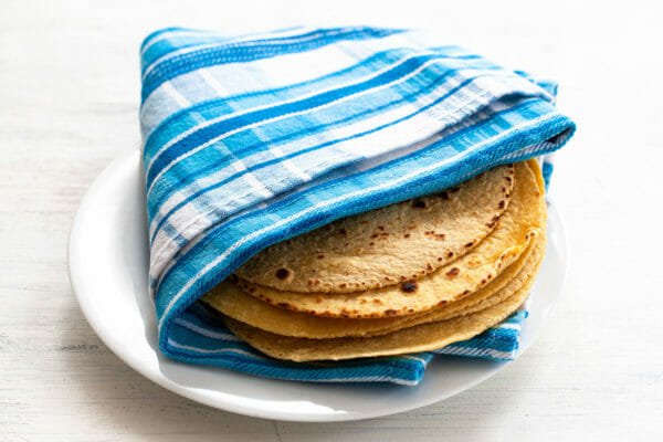 Corn tortillas wrapped in a kitchen towel for easy fish tacos.
