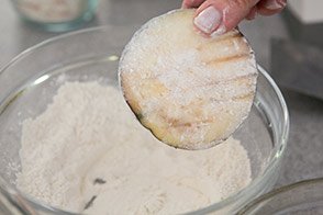 Slices of eggplant are dredged in flour to make eggplant parmesan.