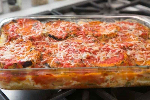 Baked eggplant parmesan in a casserole dish sitting on the stove.